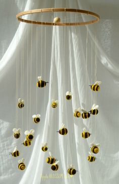 a mobile made out of bees hanging from a white curtain with strings attached to it