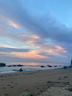 a beach with rocks and water under a cloudy sky