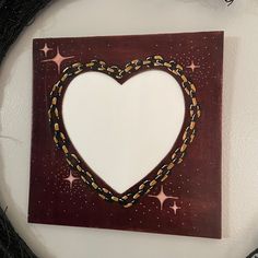 a heart shaped frame with chains hanging on the wall next to a wreath ornament