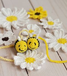 two crocheted yellow and white flowers with faces on them, sitting next to each other