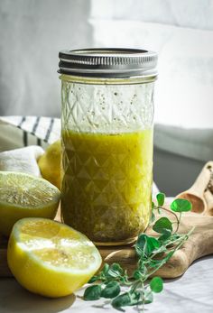 a jar filled with green liquid next to sliced lemons