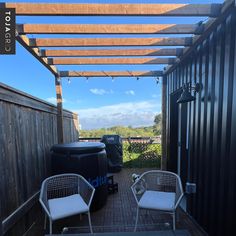 two white chairs sitting on top of a wooden deck next to a black container with a hot tub