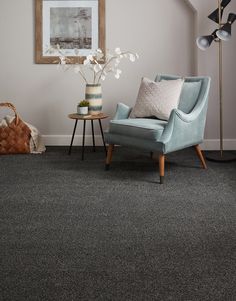 a living room with gray carpeting and a blue chair