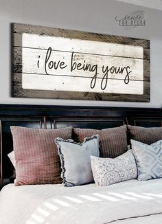 a bed that has pillows on it and a sign above the headboard saying i love being yours