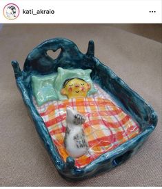 a ceramic cat laying on top of a bed