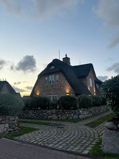 a brick house with a thatched roof at dusk