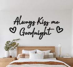 a bedroom with a bed, nightstand and wall art that says always kiss me goodnight