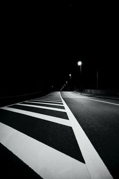 a black and white photo of a street at night with no cars on the road