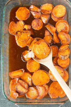 cooked sweet potatoes in a glass casserole dish with a wooden spoon on the side