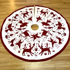 a round christmas tree skirt with reindeers and snowflakes on the bottom in red