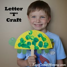 a young boy holding up a paper plate with the words letter t'n craft on it