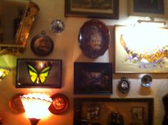 a wall with many framed pictures and lights on it's sides, including a butterfly