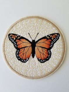 an embroidered patch with a butterfly on it's back and the wings are orange