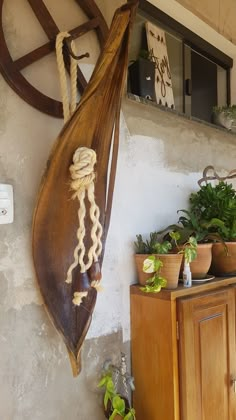 a wooden plant hanger hanging from the side of a wall next to potted plants