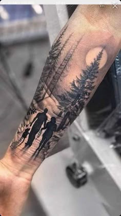 a person with a tattoo on their arm that has two people walking in the woods