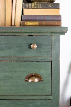 a green dresser with books on top of it