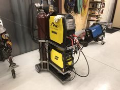 a yellow and black machine in a room with other equipment on the wall behind it