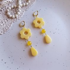 two pairs of yellow earrings sitting on top of a white plate