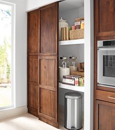 a kitchen with wooden cabinets and stainless steel trash can in the corner next to it