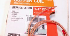 the copper colored wire is connected to an orange and white box with red labels on it