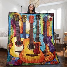 a woman holding up a quilt with guitars on it