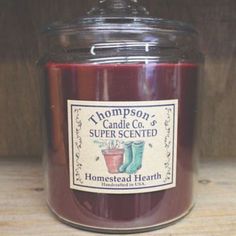 a candle with a label on it sitting on a wooden table in front of a wood paneled wall