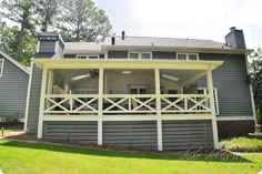 a large gray house with white railings on the front porch and covered patio area