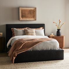 a bedroom with a bed, nightstands and pictures on the wall above it is shown