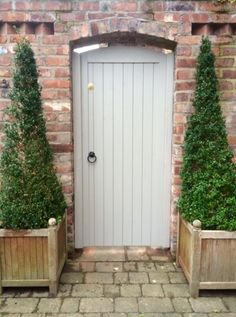 two wooden planters sitting next to each other on a brick walkway near a white door