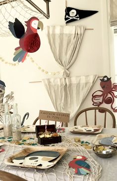 a table topped with plates covered in paper cut outs and pirate flags hanging from the ceiling