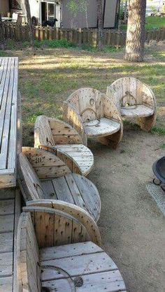 several wooden benches sitting on top of a dirt field next to a fire pit and picnic table