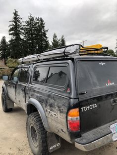 a black toyota pickup truck parked in a parking lot with snow on the roof and skis on top