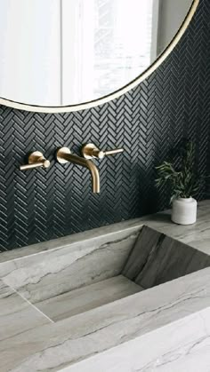 an instagramted photo of a bathroom sink with gold faucets and black herringbone tile