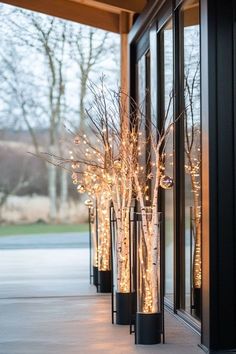 lighted branches in black vases on the side of a building with large glass windows