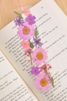 an open book with pink and purple flowers on it