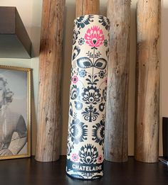 a tall vase sitting on top of a wooden table next to two framed pictures and wood poles