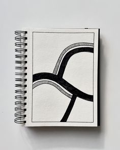 a spiral notebook with black and white lines on the cover, next to a pen