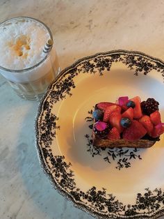 a piece of cake on a plate next to a glass of milk and strawberries