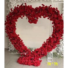 a large heart shaped wreath with red roses on the bottom and white flowers in the middle