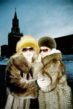 two women standing next to each other in front of a building