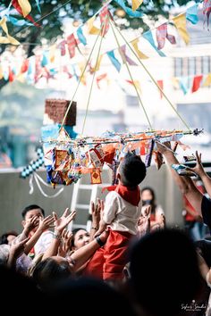 a group of people standing around each other in front of a building with kites hanging from it's ceiling