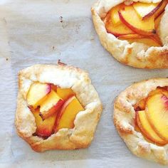 three peach pies sitting on top of a piece of parchment paper next to each other