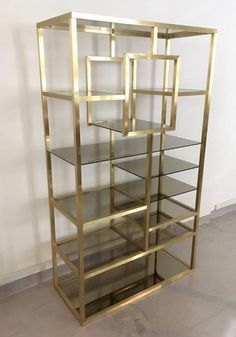 a gold and glass shelving unit in an empty room