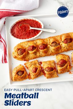 a white plate topped with pigs in a blanket next to a bowl of ketchup