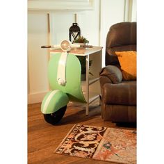 a green scooter sitting on top of a wooden floor next to a chair