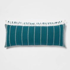 a blue and white striped pillow with tassels on the bottom, sitting on a white surface