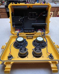 an open yellow case with two speakers and wires attached to the inside of it, sitting on top of a counter