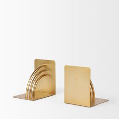 two brass bookends with curved sections on each side, against a white background