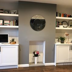 a living room filled with furniture and bookshelves next to a wall mounted clock