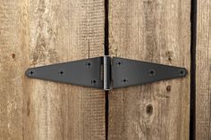 a black metal door hinge on a wooden wall